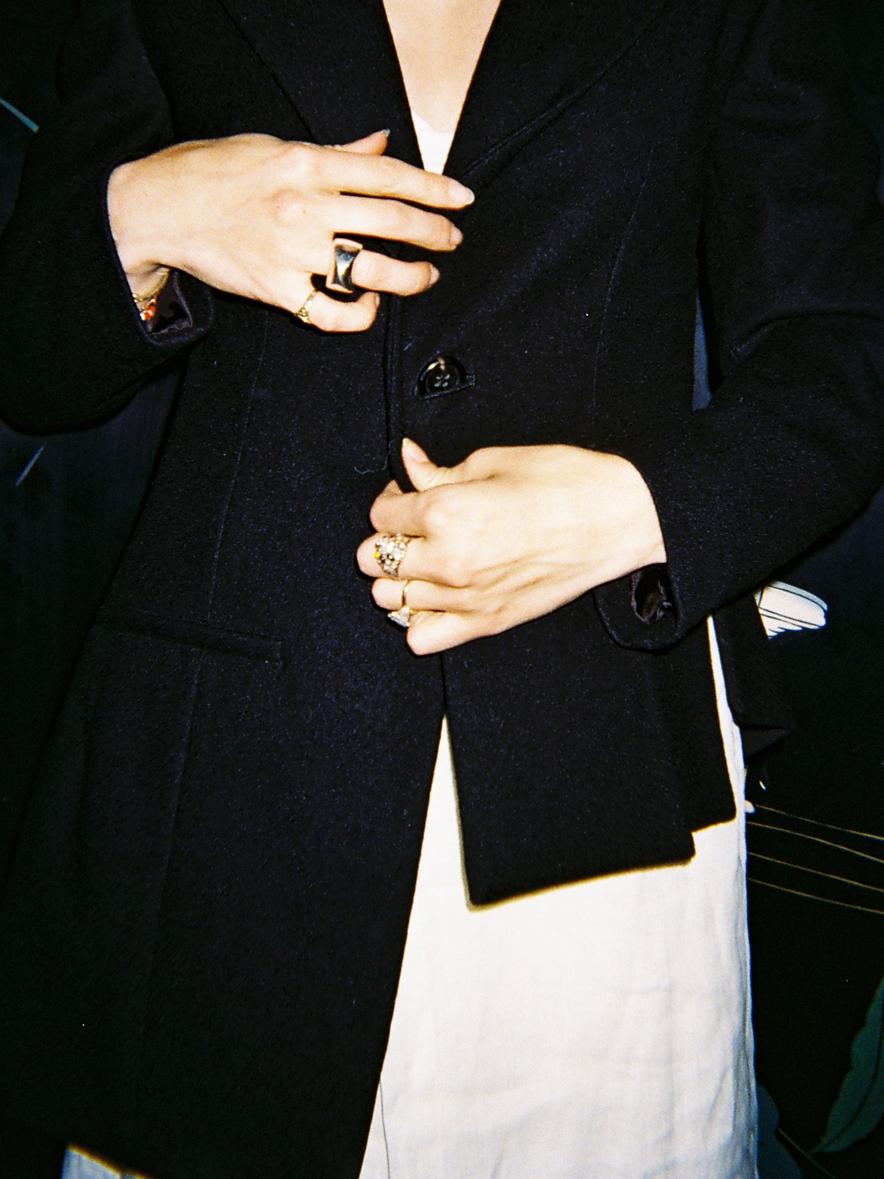 Person wearing a black blazer with visible jewelry